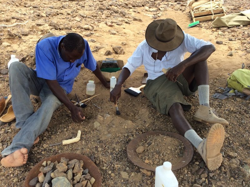 Cyprian Nyete (links) und Isaiah Nengo (rechts) schützen Alesi beim Ausgraben mit Zahnstocher, Pinsel und einem Härter. Foto: © Isaiah Nengo