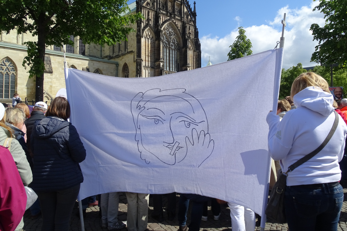 Streikende Katholikinnen mit stilisiertem Porträt einer Frau mit zugeklebtem Mund – dem Symbolbild der Initiative Maria 2.0. 